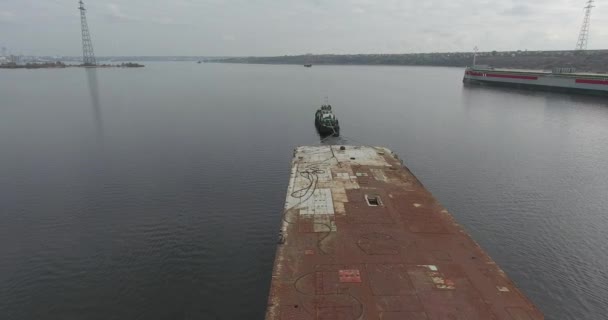 Bovenaanzicht van een rivier-sleepboot die een roestige aak langs rustige rivier trekt. Zomerdag — Stockvideo