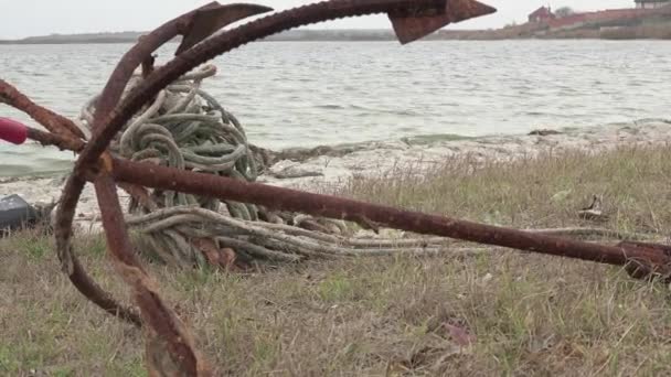 Old rusty anchor lies on the river bank — Stock Video