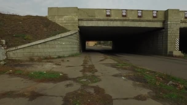 Movimento de um ciclista com uma câmera sob uma ponte ferroviária de concreto — Vídeo de Stock