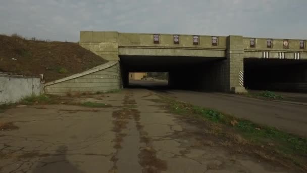 Движение велосипедиста с камерой под бетонным железнодорожным мостом — стоковое видео