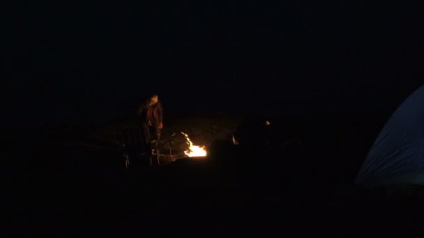 成熟した男は休憩し、夜の山でのたき火用の木の乾燥 branche をカット — ストック動画