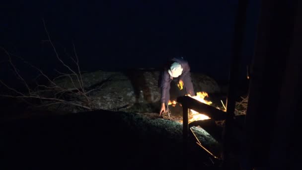 Hombre maduro rompe y corta rama seca de árbol para hoguera en las montañas por la noche — Vídeos de Stock