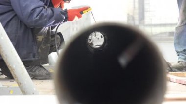 Kaynak yapan adam borularda kaynakçılık yapıyor. Kıvılcımlar uçuşur, örümcek ağda oturur metal boruda