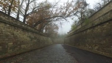 Mermi tuğlalarından yapılmış duvarlar arasında taş gibi eski bir kaldırımda hareket. Sonbahar şehri sisli