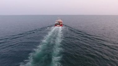 Açık denizde yelken açan bir geminin arkasından hava manzaralı uçuş. Katamaran araştırma gemisi