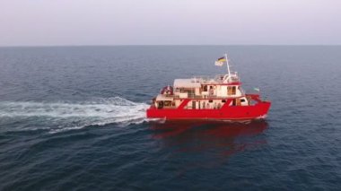 Hava görüntüsü. Araştırma gemisi açık denizlerde yelken açıyor. Kırmızı katamaran iki motorla gider.