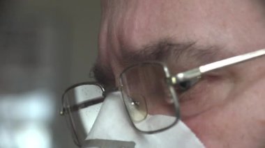 Bilim adamı, gazlı bez maskeli, virüs korumalı ve gözlüklü yetişkin bir adam gözlerindeki endişeyle ekrana bakıyor.