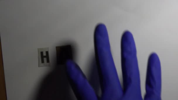 白色背景的题词 Hacked 是由戴着蓝色手套手拿着镊子 从报纸上剪下来的字母组成的 — 图库视频影像