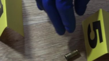 Suç araştırmacısı mavi eldivenli, çantada mermi kovanları var, suç mahallinde inceleme yapmak için.