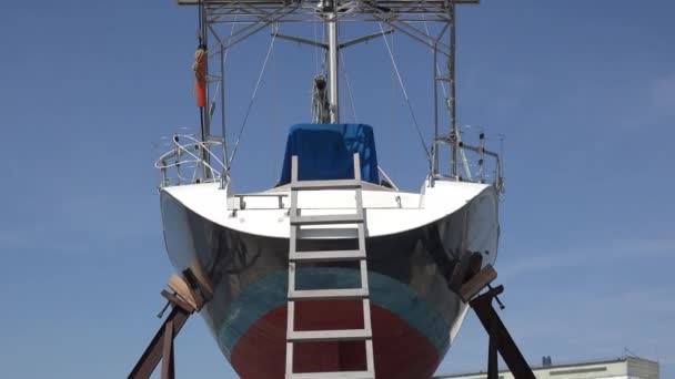 Bateau sur cale dans la marina pendant la réparation et le nettoyage des coquilles sur le fond, mât haut sans voiles et panneaux solaires 