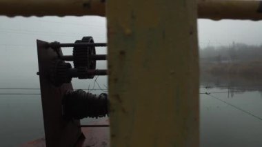 Sabahın erken saatlerinde sisli bir yaz nehri üzerinde, pantone demir köprüsünden, paslı metal teçhizatlı, dişli.