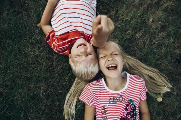 Närbild litlle bror och syster ligger på gräset leende och — Stockfoto