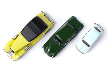 Beyaz arka planda üç oyuncak eski araba var.