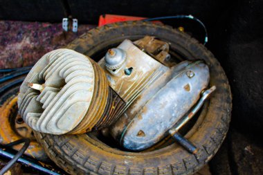 Eski motosiklet motoru tekerleğin üzerinde yatıyor.