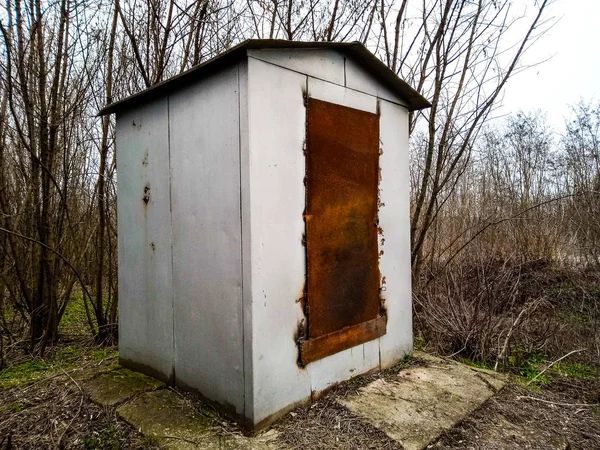 A metal booth with rusty doors stands in a forest belt — Stock Photo, Image