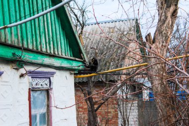 Duvardaki eski yel değirmeni. Kiremit çatıda yürüyen bir kedi. Bacadan duman çıkıyor.