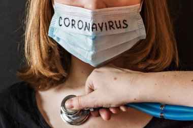 Yüzünde buzlu maskeli bir kızın şüpheli koronavirüsle yakın plan portresi. Doktor onu stetoskopla dinliyor. Yeni Coronavirus-covid-2019. Çin salgını..