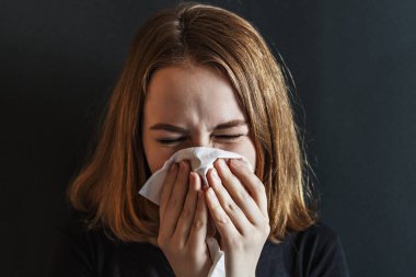 Burnu buruşuk, burnu kırışık, ateşi çıkmış, nezle olmuş, doku hapşırması geçirmiş alerji belirtileri gösteren hasta, evde öksüren, grip konsepti olan genç bir kadın. Viral enfeksiyon. Covid-2019.