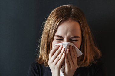 Burnu buruşuk, burnu kırışık, ateşi çıkmış, nezle olmuş, doku hapşırması geçirmiş alerji belirtileri gösteren hasta, evde öksüren, grip konsepti olan genç bir kadın. Viral enfeksiyon. Covid-2019.