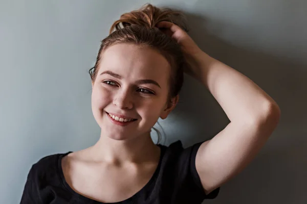 Uma Jovem Garota Sorrindo Ajusta Seu Cabelo Com Mão Contra — Fotografia de Stock