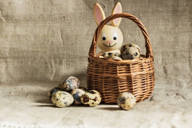 Mutlu Paskalyalar, keten arka planda sepetteki bıldırcın yumurtaları ve tahta tavşan, bahar Ortodoks ve Katolik bayramı.