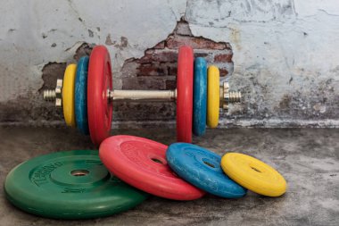 Profesyonel halterler ve klasik bir arka planda çok renkli ağırlık plakaları. Spor malzemeleri. Sağlıklı yaşam tarzı