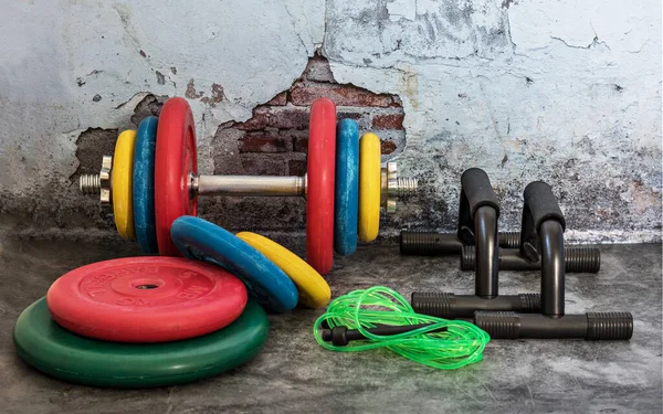 Profesyonel dambıllar, çok renkli ağırlık plakaları, atlama ipi ve vintage arka planda şınav çekimleri. Spor malzemeleri. Sağlıklı yaşam tarzı