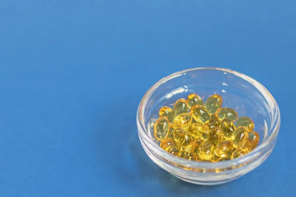 Gula Gelatinkapslar Med Vitamin Glasburk Blå Botten Läkemedelsbehandling Och Profylaktisk — Stockfoto
