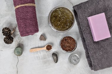Gri arka planda Spa özbakım aksesuarları var: vücut fırçası, öğütülmüş kahve, lavanta sabunu, yüz ve vücut için Terry havlusu..