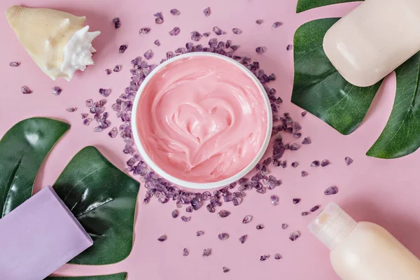 Doğal organik kozmetik ürünleri: vücut kremi, banyo tuzu, lavanta ve şeftali sabunu, duş jeli, pembe arka planda canavar yapraklı deniz kabuğu. Düz kat. Cilt bakımı ve güzellik kavramı. Spa evi.