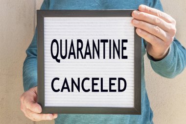 Quarantin iptal edildi yazılı bir pankart tutan bir adam var. Karantinanın sonu. Otel, kafe, yerel mağaza, hizmet sahibi, Coronavirus salgınından ve izolasyondan sonra misafirlerle tanışıyor.