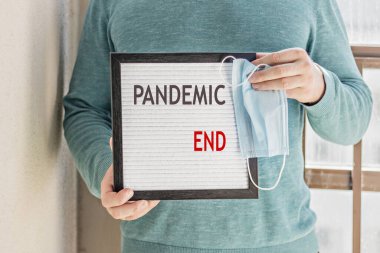 Hoş geldin mesajı pandemic sonlu bir pankart tutan bir adam. Karantinanın sonu. Otel, kafe, yerel mağaza, hizmet sahibi, Coronavirus salgınından ve izolasyondan sonra misafirlerle tanışıyor.