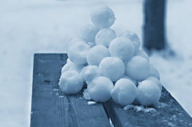 A slide of stuck snowballs on a wooden bench in the yard in classic blue. clipart