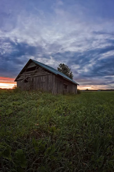 Nubes al atardecer y una vieja casa de granero — Foto de Stock
