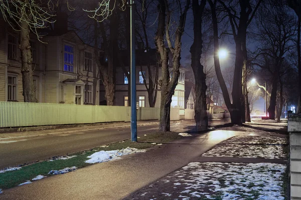 公園に続く道は エストニアの首都タリンの街灯に照らされています 古い木造住宅の壁に劇的な影を作り出します — ストック写真