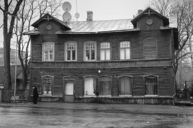 Yaşlı bir bayan daha iyi günler gören bir evin önünden geçiyor. Bu tür binalar Estonya 'nın başkenti Tallinn' in bazı kısımlarında tipik..