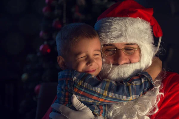 Retrato de un niño feliz con Papá Noel junto al árbol de Navidad —  Fotos de Stock