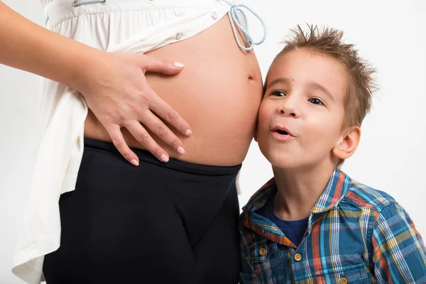 Portret van een kind en een zwangere vrouw. Hij luistert naar wat is in de buik van mijn moeder gaande er. Foto closeup — Stockfoto