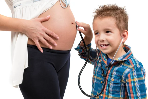 Portret van een kind en een zwangere vrouw. De jongen gebruikt een stethoscoop. Hij luistert naar wat is in de buik van mijn moeder gaande er. Foto closeup — Stockfoto