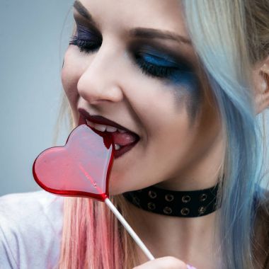 Portrait of a beautiful young woman with a candy in the form of a heart. Makeup in the style of Halloween. Photo closeup clipart