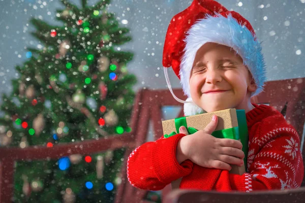 Retrato de un niño feliz con un regalo en el fondo de un árbol de Navidad — Foto de Stock