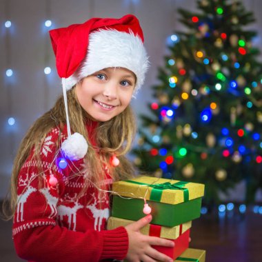 Bir Noel ağacı arka plan üzerinde bir hediye ile mutlu bir çocuk portresi