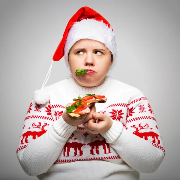 Onun elinde büyük bir sandviç ile şişman bir kadın portresi. O bir neşeli Noel kazağı ve Santa şapka giyiyor. Tatil günlerinde overeating