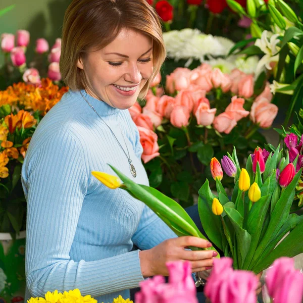 Çiçekçi iş yeri. Çiçekçi dükkanı. Gülümseyen güzel kadın portresi Lale bir buket