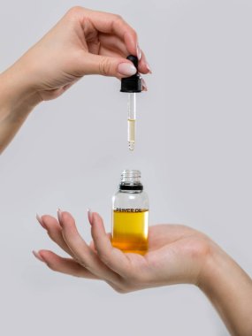 Kadınların elleri yüzüne petrol şişe. Gri bir arka plan bir astar yakın çekim fotoğraf