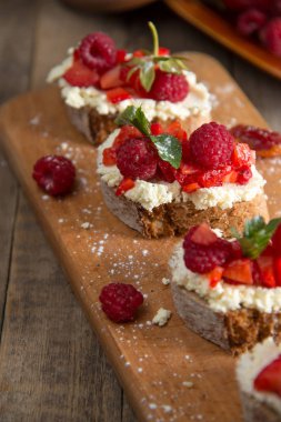 Meyve Ahududu ve ahşap bir bo üzerinde süzme peynir ile brusquest