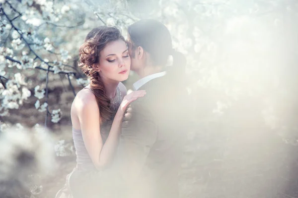 Young woman hugging a man in the flowered garden — Stock Photo, Image