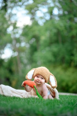 Bebek gibi bir bunny havuç oyuncak açık havada yeşil çimenlerin üzerinde ile şapkalı