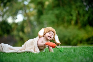 Bebek gibi bir bunny havuç oyuncak açık havada yeşil çimenlerin üzerinde ile şapkalı
