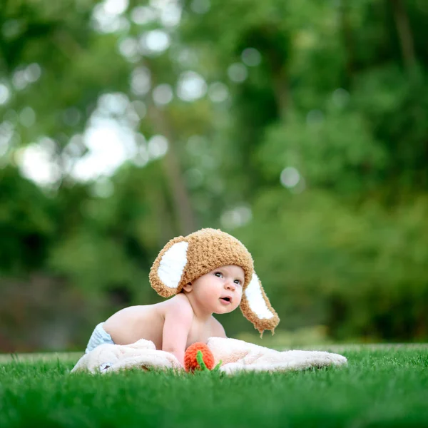Bebek gibi bir bunny havuç oyuncak açık havada yeşil çimenlerin üzerinde ile şapkalı